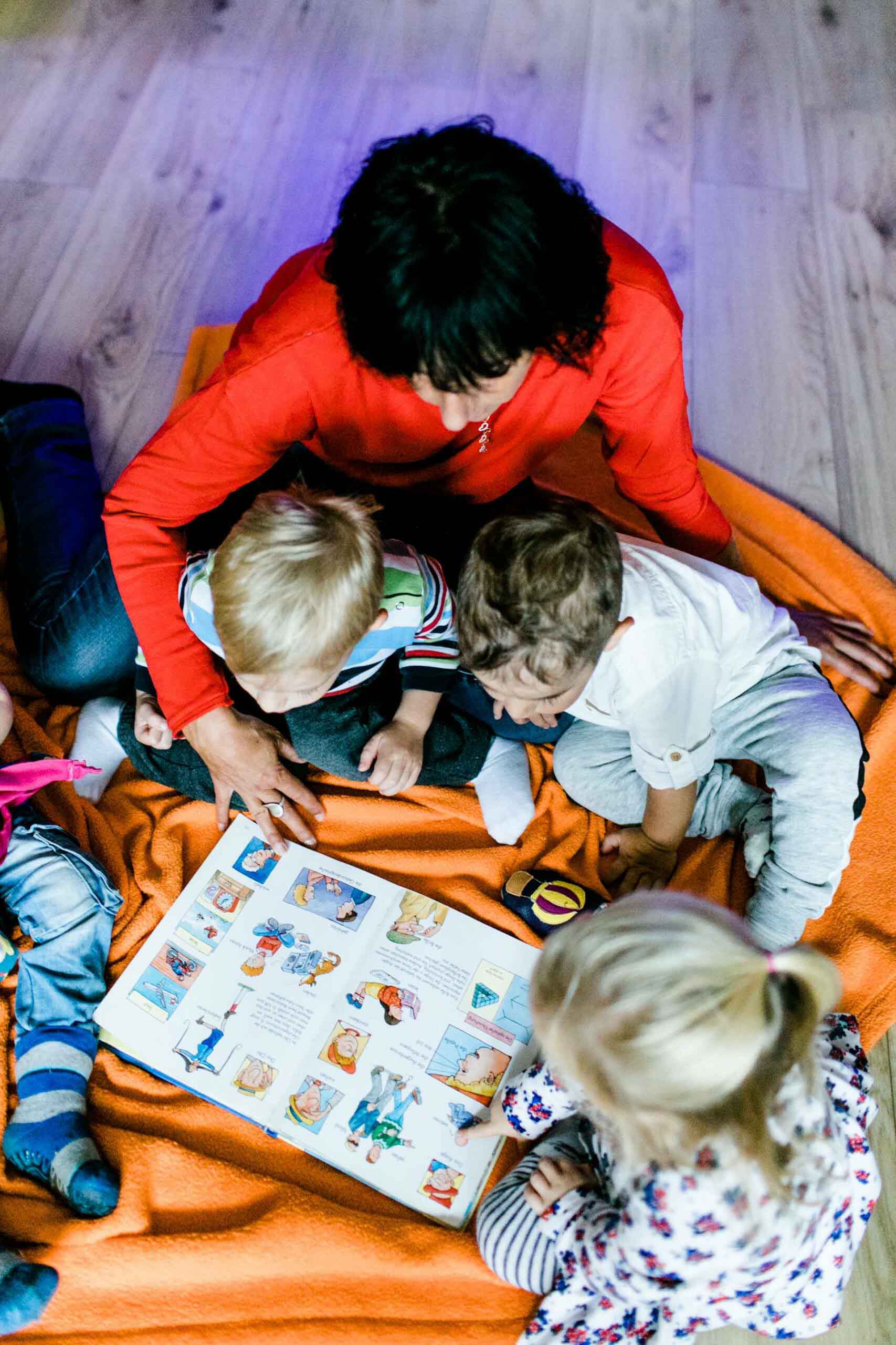 Tagesmutter liest mit Kindern ein Buch, Kinderbetreuung