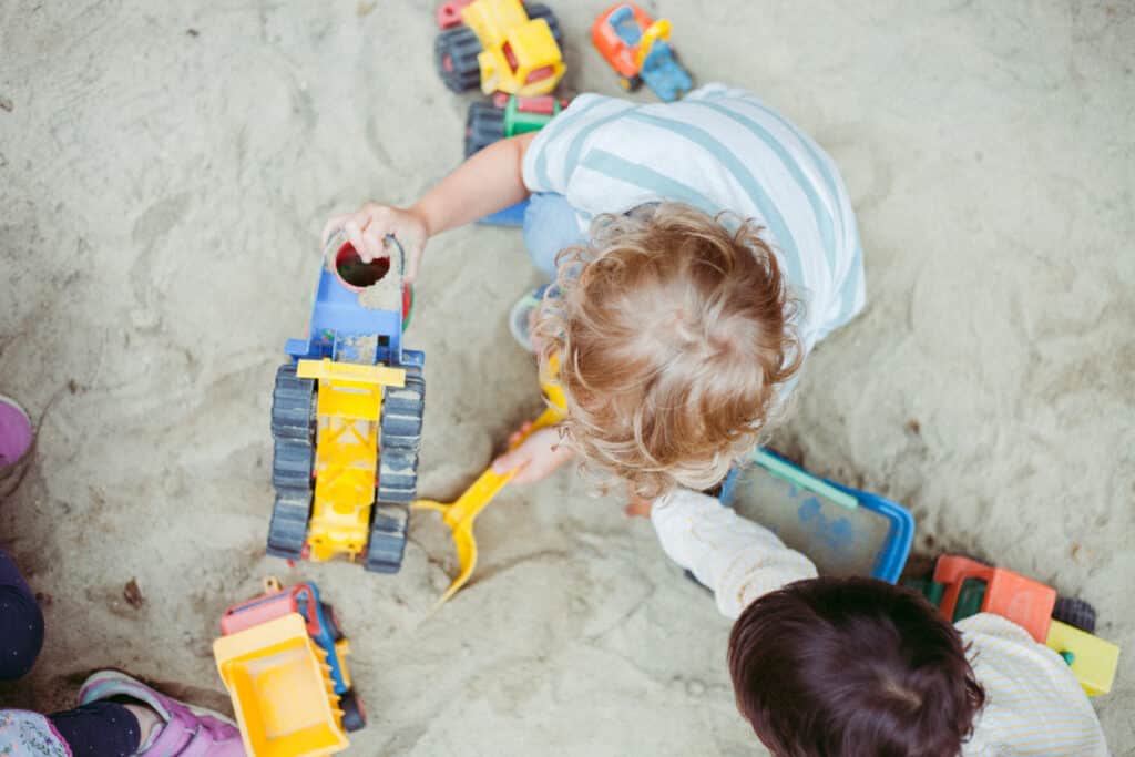 Kind in einer Kinderkrippe am Sand Spielen, mit Spielzeugbagger