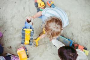 Kind in einer Kinderkrippe am Sand Spielen, mit Spielzeugbagger